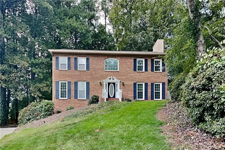 Brick exterior residence with a prominent arched window, white-framed windows, and dark blue shutters