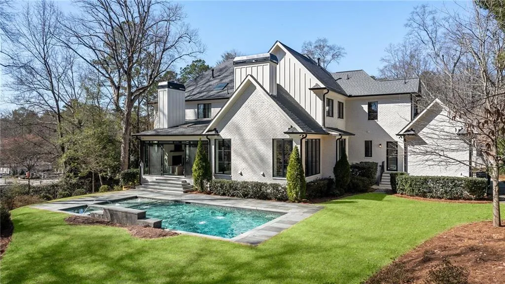 Back of house featuring board and batten siding, an outdoor pool, brick siding, and a yard