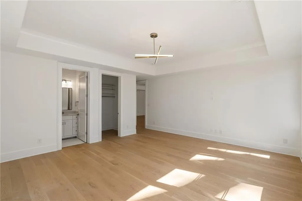 Unfurnished bedroom featuring light wood-style floors, baseboards, and a tray ceiling