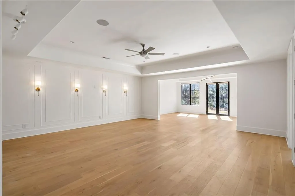 Unfurnished room with light wood-type flooring, a raised ceiling, a ceiling fan, and baseboards