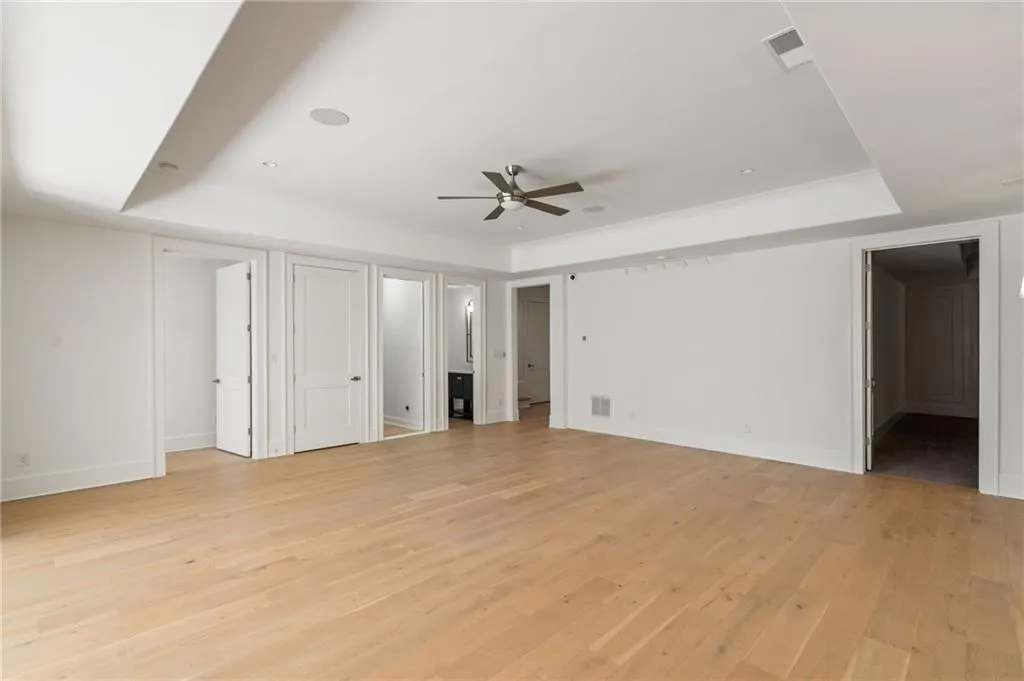 Unfurnished bedroom featuring light wood-type flooring, a raised ceiling, visible vents, and baseboards