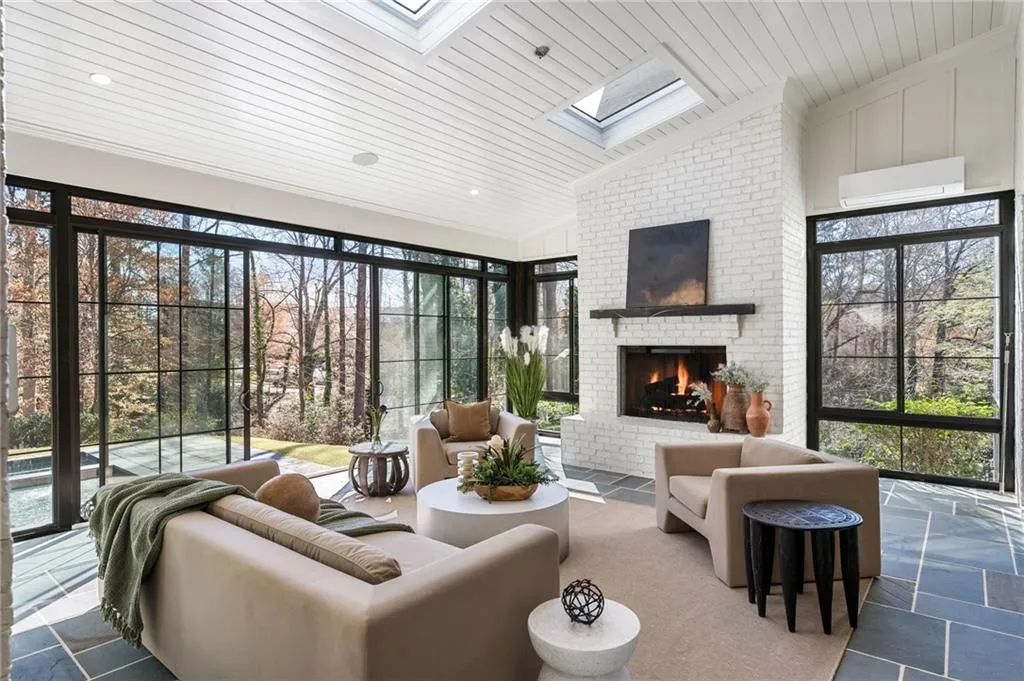Living room featuring wooden ceiling, stone tile floors, an AC wall unit, a brick fireplace, and lofted ceiling with skylight