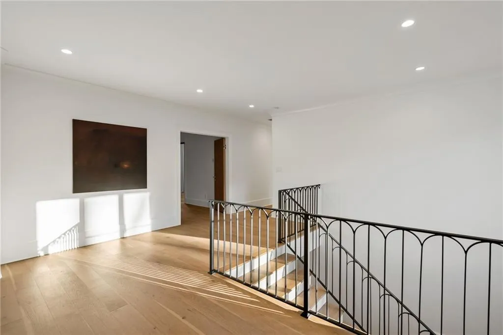 Hallway featuring ornamental molding, wood finished floors, and an upstairs landing