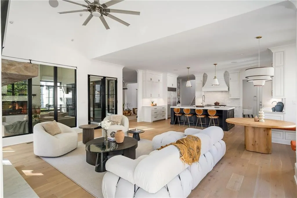 Living room with ceiling fan, a lit fireplace, and light wood-style floors