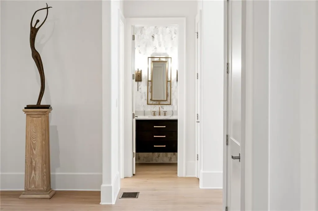 Hallway featuring light wood-style floors, baseboards, visible vents, and a sink