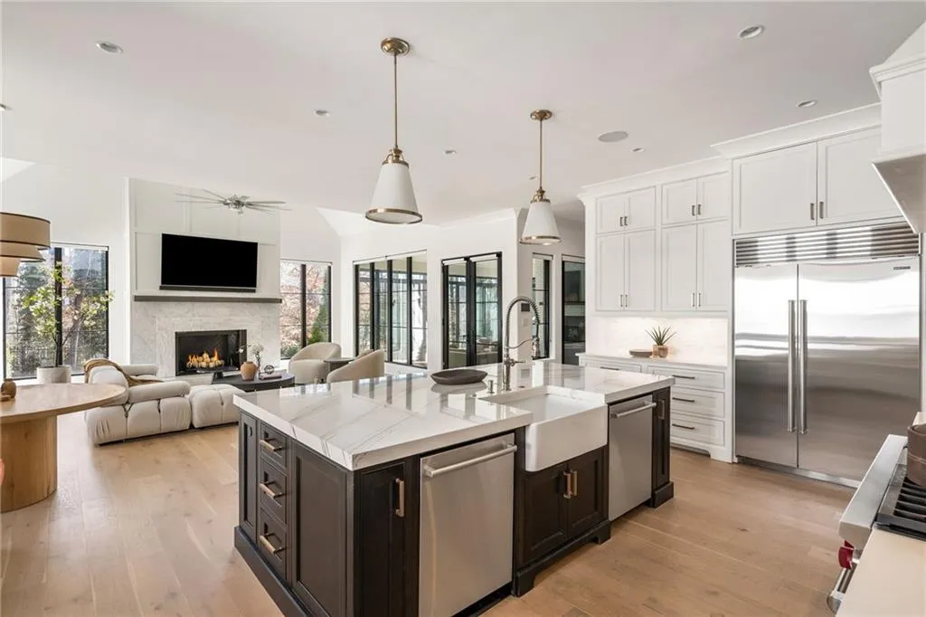 Kitchen with a warm lit fireplace, a sink, white cabinets, appliances with stainless steel finishes, and a wealth of natural light