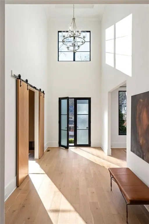 Foyer entrance with a notable chandelier, ornamental molding, a towering ceiling, and light wood-style floors