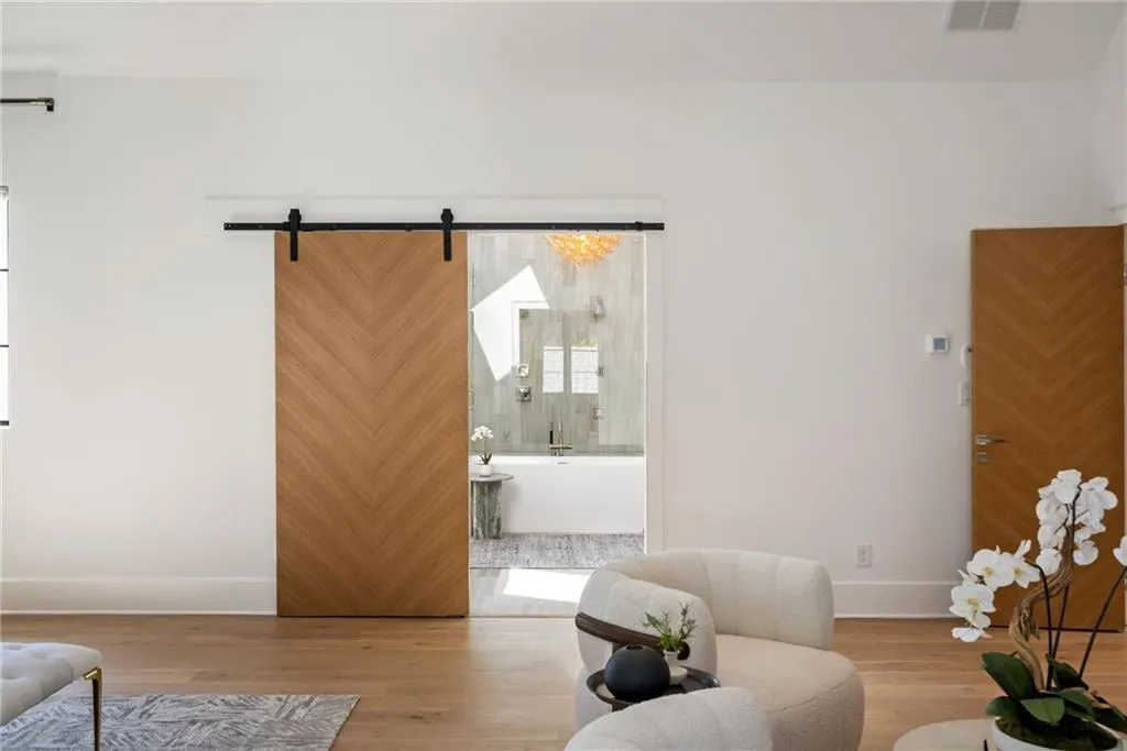 Sitting room featuring a barn door, wood finished floors, visible vents, and baseboards