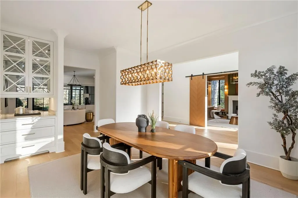 Dining room with ornamental molding, baseboards, light wood finished floors, and a barn door