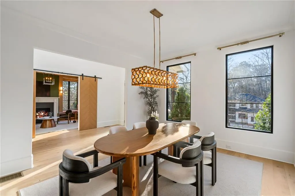 Dining area with a barn door, light wood-style flooring, visible vents, baseboards, and a lit fireplace