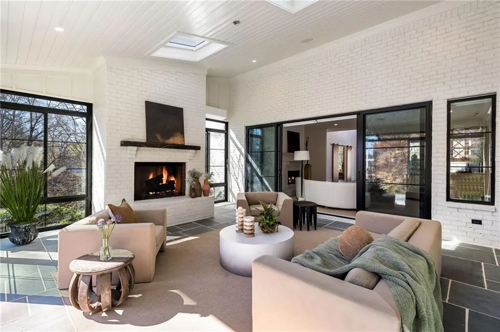 Living area with a skylight, a fireplace, a high ceiling, ornamental molding, and brick wall