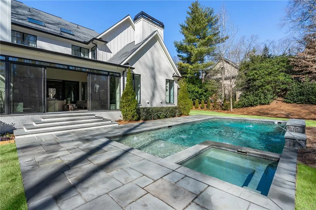 Back of house with an in ground hot tub, brick siding, board and batten siding, and a patio area