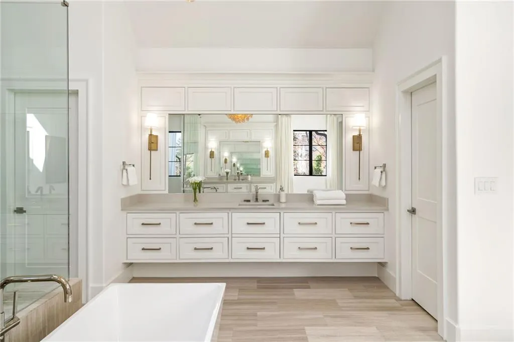 Bathroom with a soaking tub, a shower with shower door, vanity, and baseboards