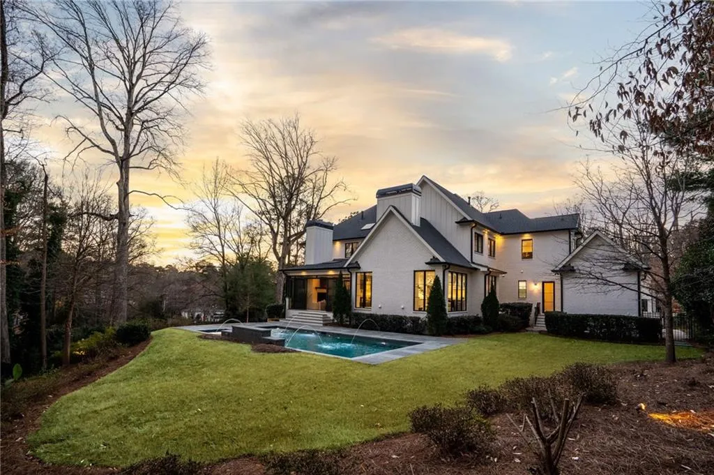 Back of property at dusk featuring an outdoor pool and a yard