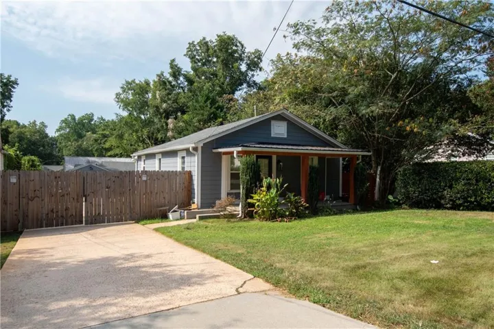 Siding exterior, covered porch, mature landscaping, concrete driveway, and wood fence
