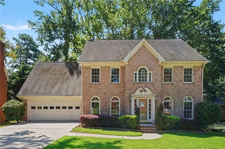 Brick exterior with gabled roofline, arched windows, and an attached two-car garage