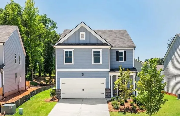 Two-story property featuring light blue siding with white trim, a two-car garage, and a covered porch entry