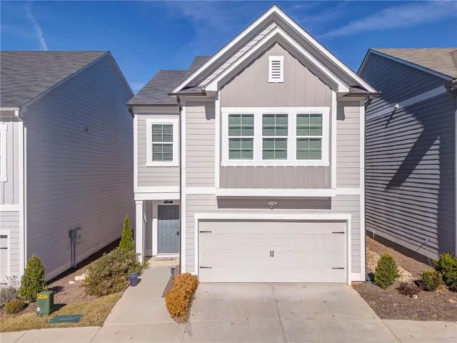 View of front of house with board and batten siding, driveway, and a garage
