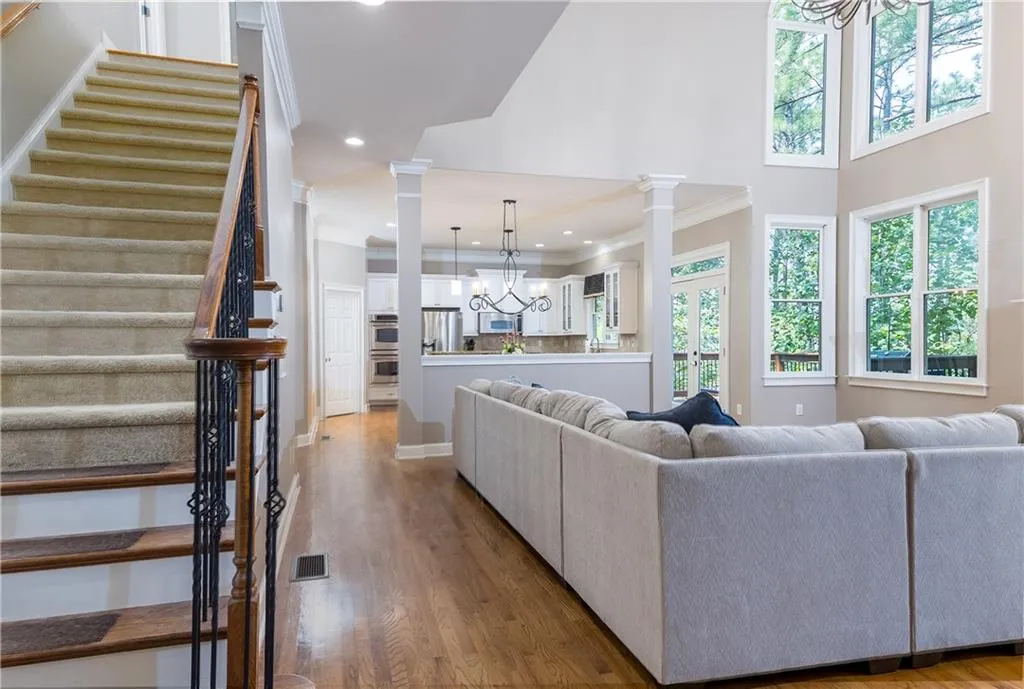 Living room with a chandelier, stairs, a towering ceiling, wood finished floors, and crown molding