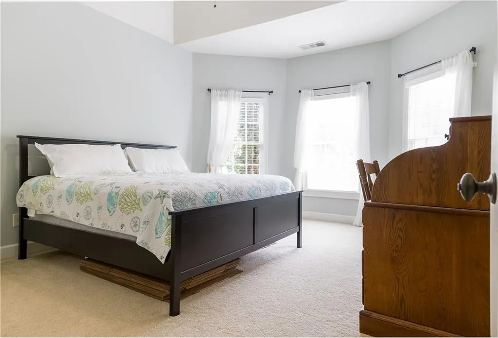 Bedroom featuring light colored carpet and multiple windows