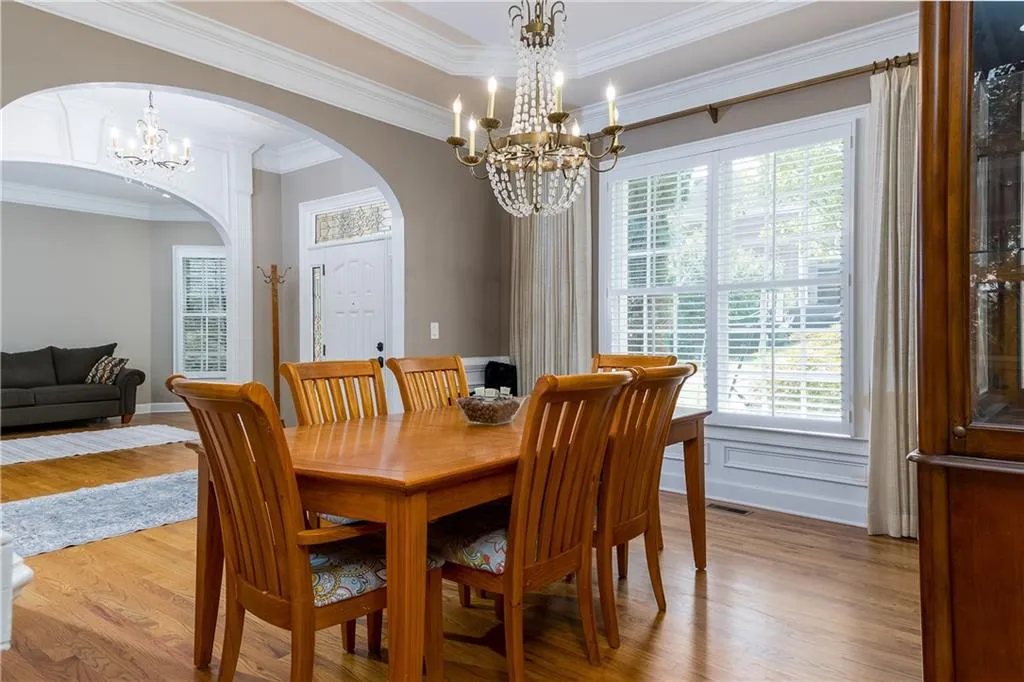 Dining room with a chandelier, plenty of natural light, ornamental molding, wood finished floors, and arched walkways