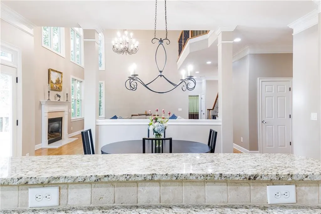 Kitchen featuring crown molding, a fireplace with flush hearth, wood finished floors, plenty of natural light, and light stone counters