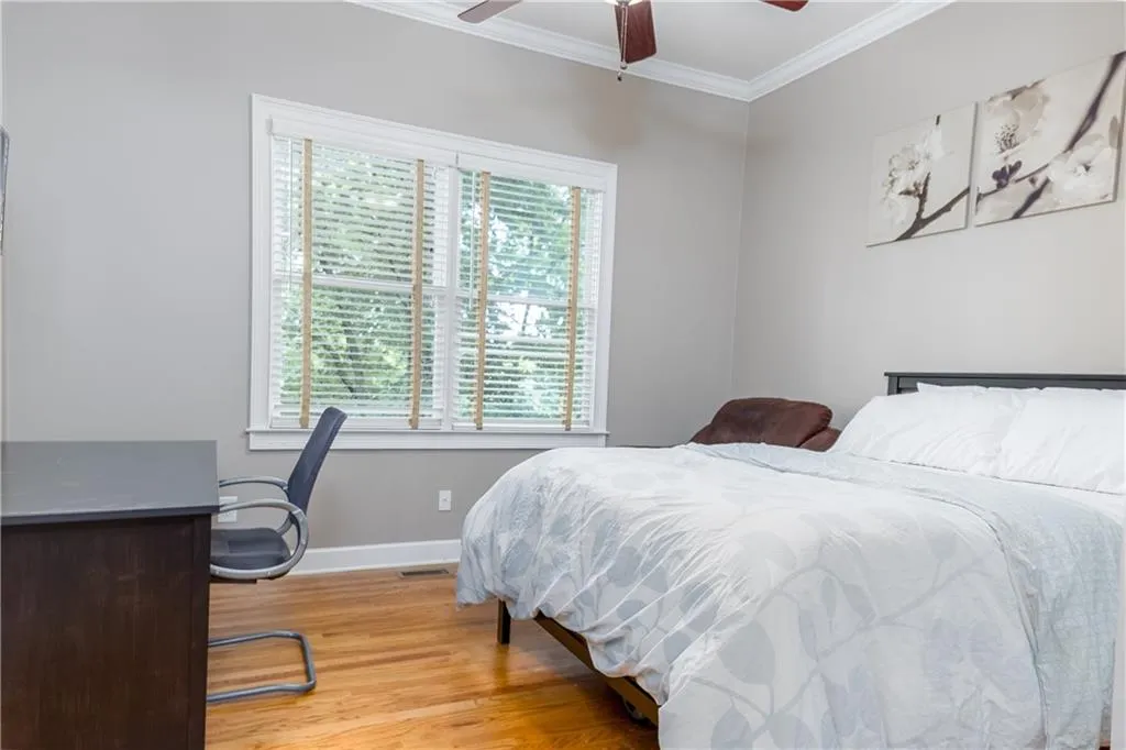 Bedroom with ornamental molding, light wood-style floors, an office area, and a ceiling fan