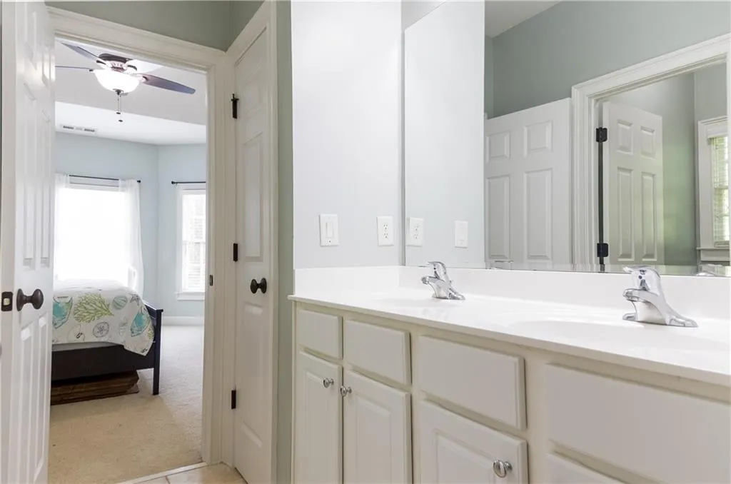 Full bath with double vanity, connected bathroom, and ceiling fan