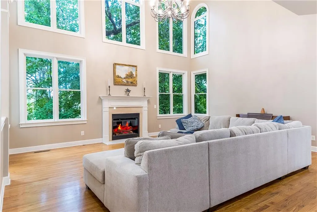 Living area featuring a chandelier, a glass covered fireplace, a high ceiling, and light wood finished floors