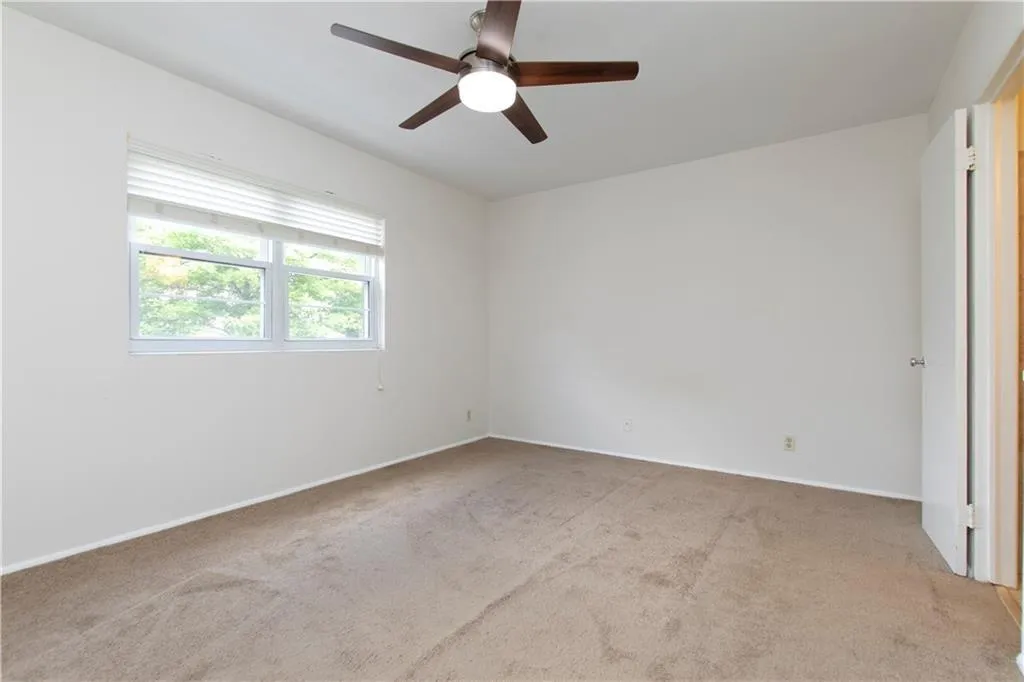 Unfurnished room featuring light carpet and ceiling fan