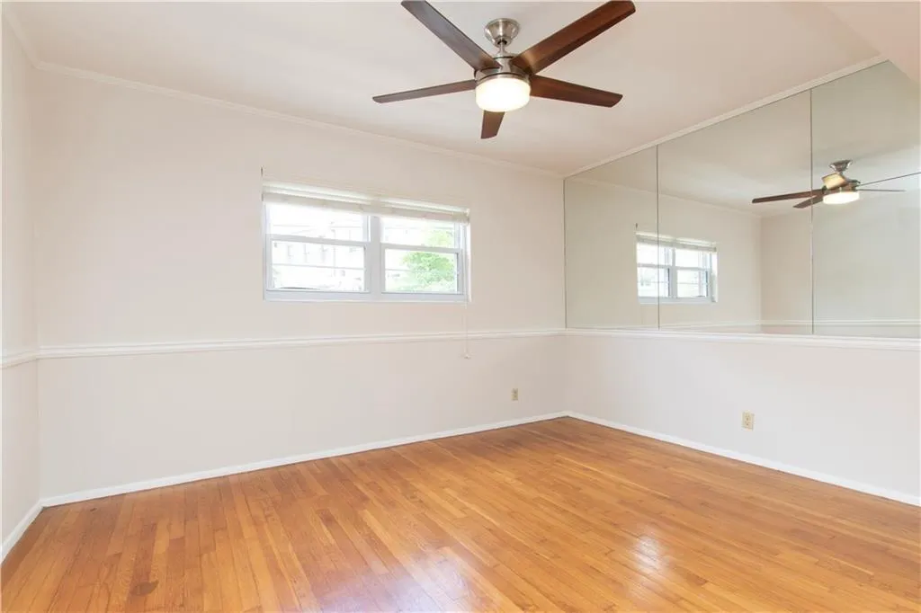 Spare room with plenty of natural light, light wood-style flooring, ceiling fan, and ornamental molding