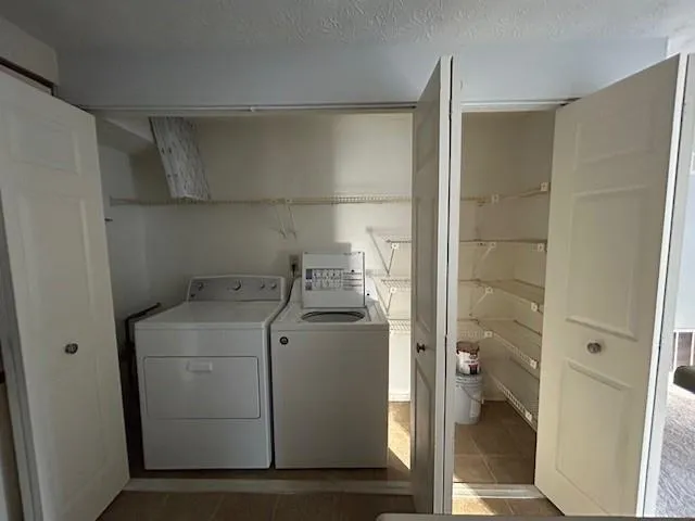 Laundry room featuring washer and dryer, a textured ceiling, and dark tile patterned floors