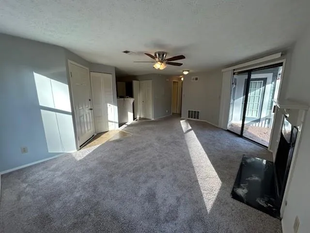 Unfurnished living room with carpet, a textured ceiling, and ceiling fan