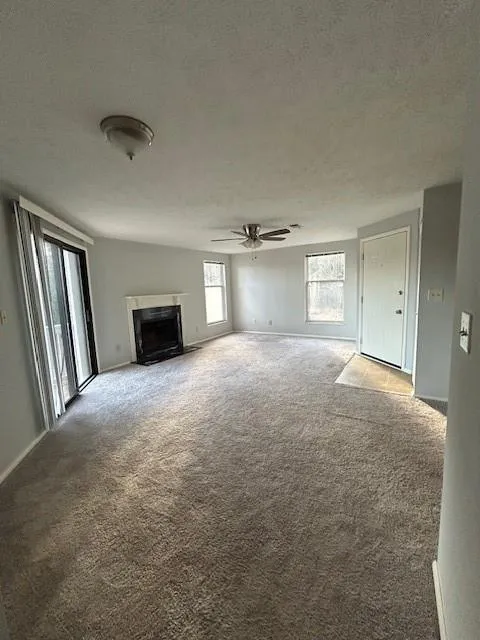 Unfurnished living room with carpet floors, a textured ceiling, and ceiling fan