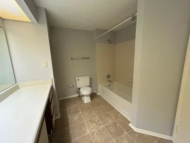 Full bathroom with a textured ceiling, toilet, vanity, and shower / bath combination