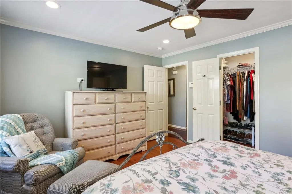 Bedroom with ornamental molding, wood-type flooring, ceiling fan, a closet, and a walk in closet
