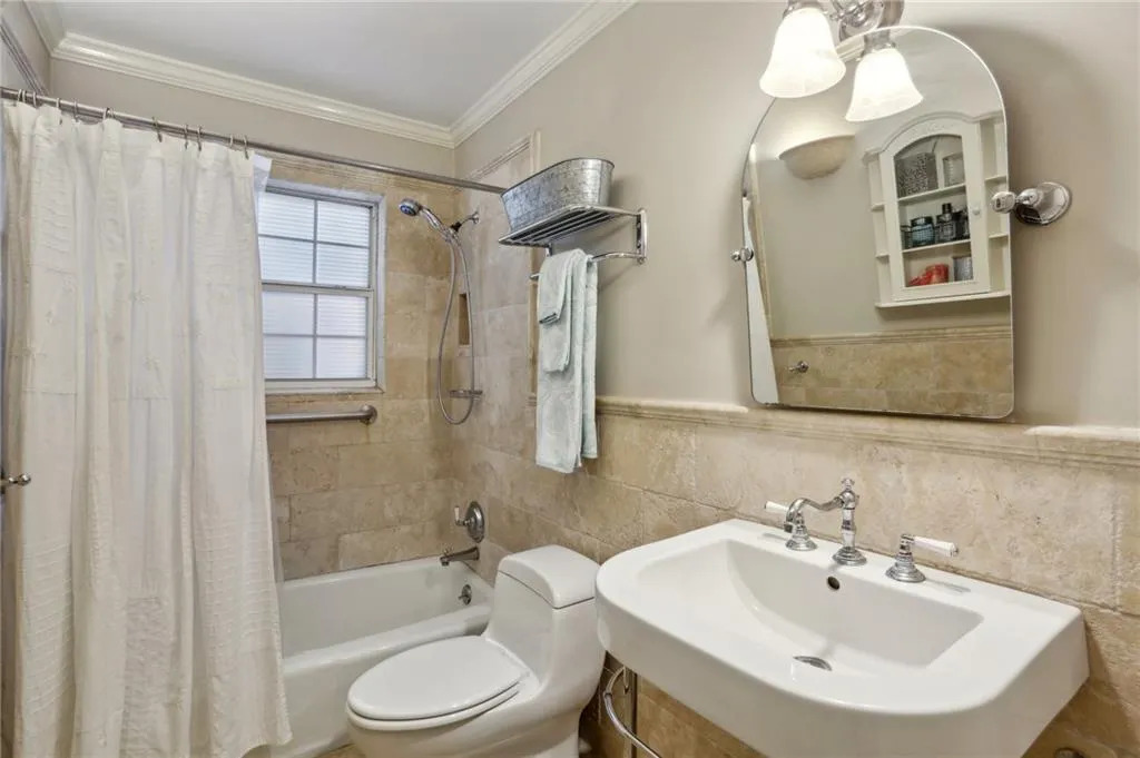 Full bathroom featuring toilet, backsplash, sink, tile walls, and shower / tub combo with curtain