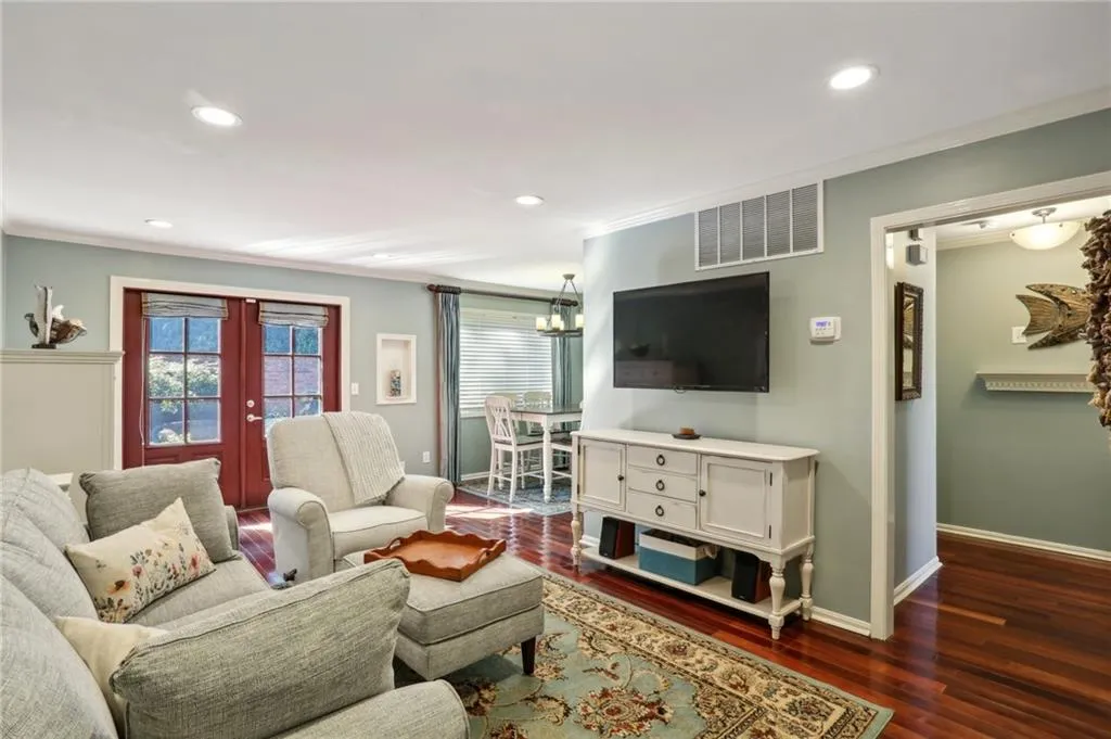 Living room with dark hardwood / wood-style floors, a chandelier, and ornamental molding