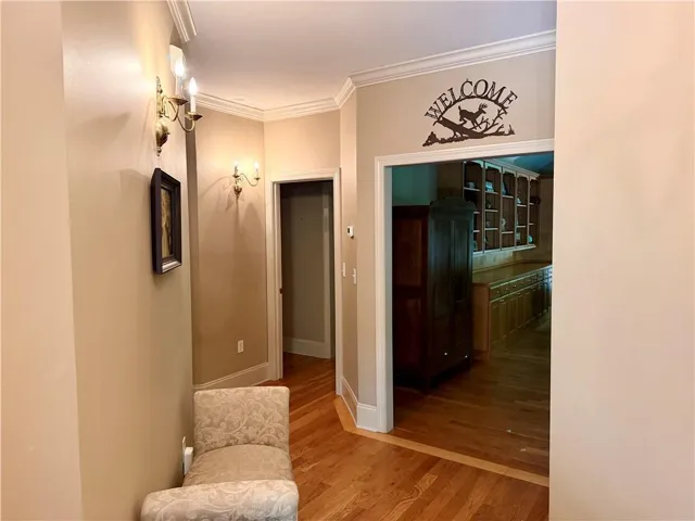 Hardwood flooring, crown molding, wall sconces, built-in cabinetry, and a wide entryway
