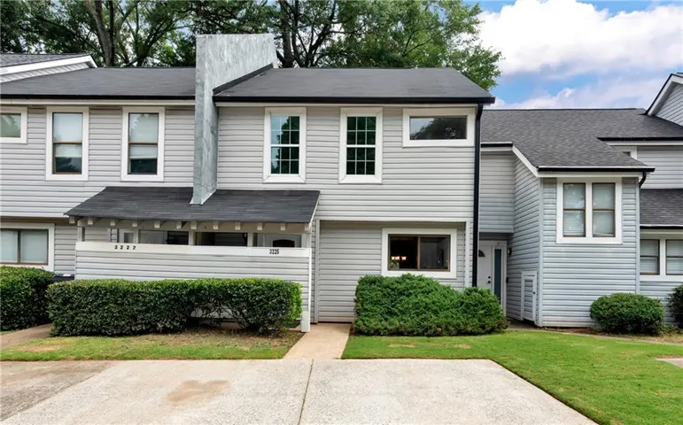 Two-story townhouse with light gray horizontal siding and a dark shingled roof