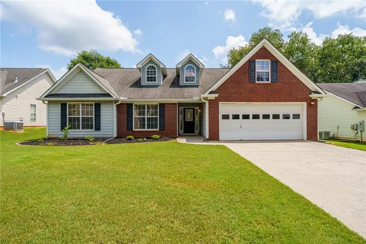 Brick and siding exterior with a two-car garage, dormer windows, and a concrete driveway