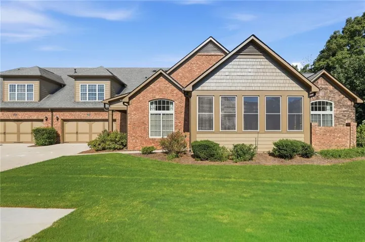 Brick and stone facade with shake and horizontal siding accents, multiple dormer windows, a three-car garage, and an arched window