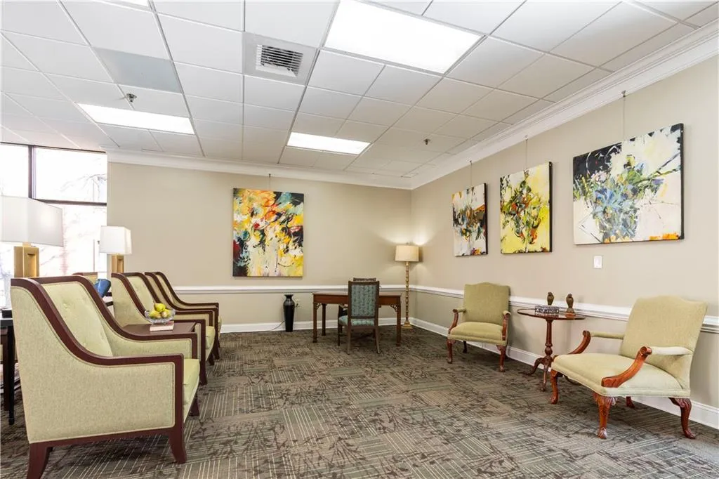 Sitting room with dark colored carpet, crown molding, and a paneled ceiling