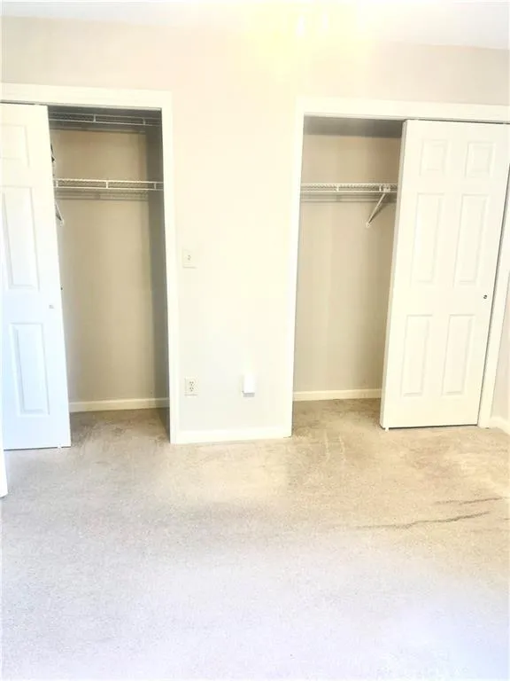 Unfurnished bedroom with baseboards, multiple closets, and carpet floors