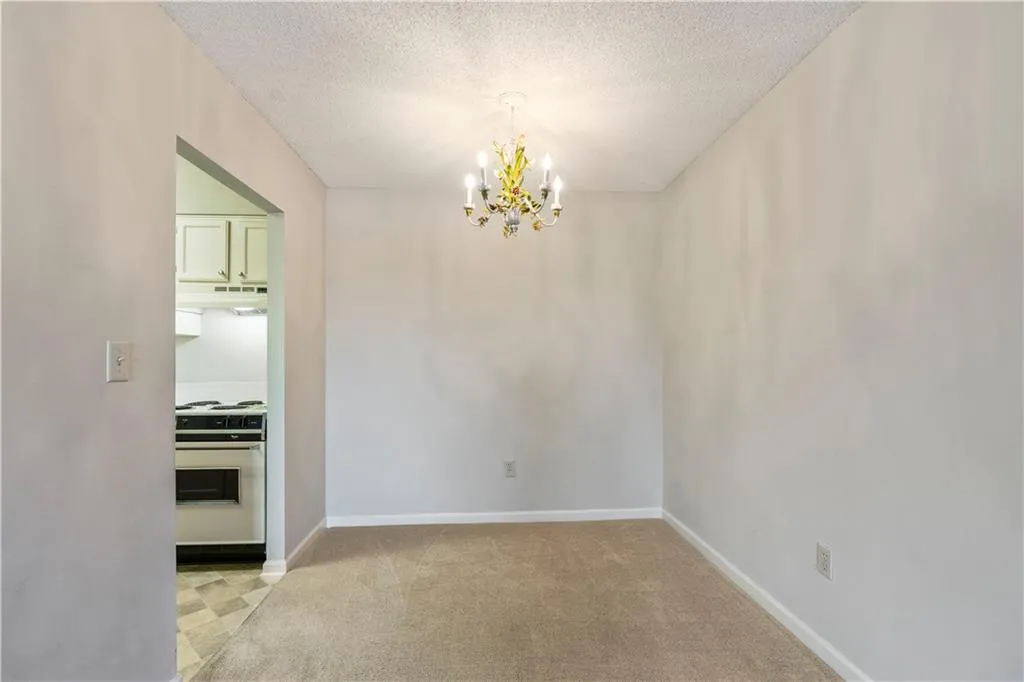 Dining area featuring light carpet, a textured ceiling, and a chandelier
