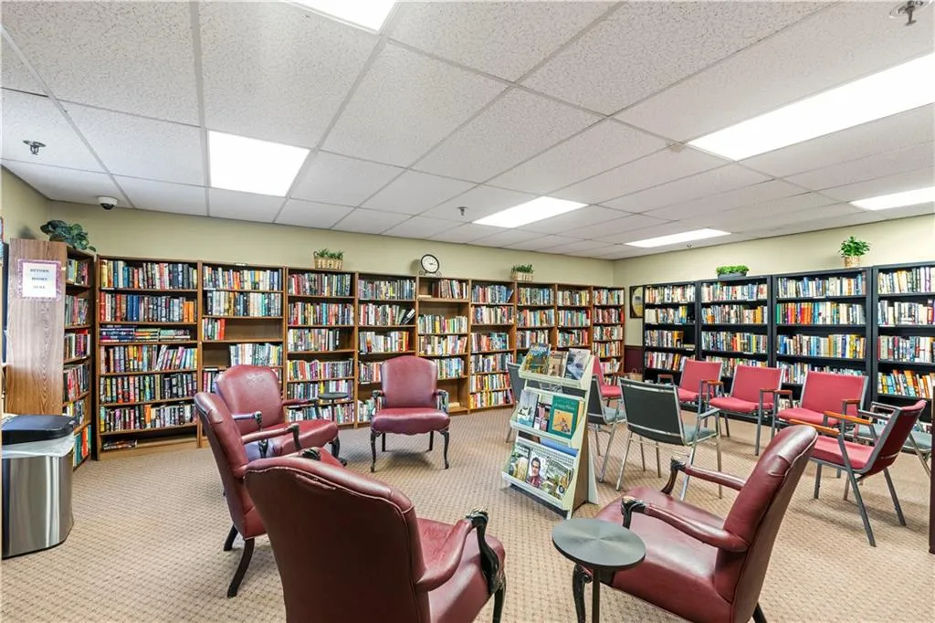 Library with bookshelves, a drop ceiling, and carpet flooring
