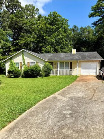 Ranch-style residence featuring a pale yellow exterior, white porch railing, and an attached single-car garage