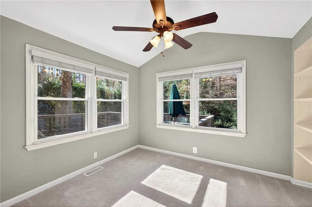 Main Floor Secondary Bedroom | Fresh Carpeted Flooring | Dual Pane Vinyl Windows | Custom Window Treatments | Views to Rear Deck + Sun Lounge | Wooded Privacy