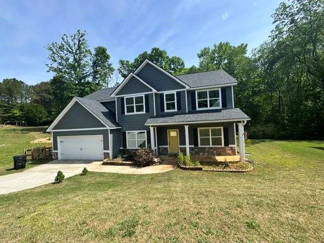 Two-story residence featuring dark gray siding, white trim, and a prominent front entry with a yellow door
