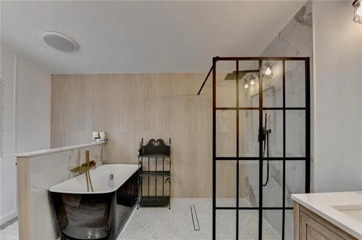 Bathroom featuring a walk in shower, a soaking tub, and vanity